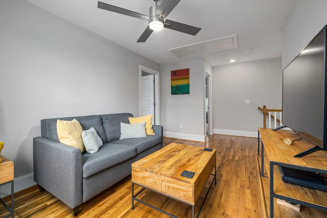 Long living room with a sofa against one wall and a wooden coffee table
