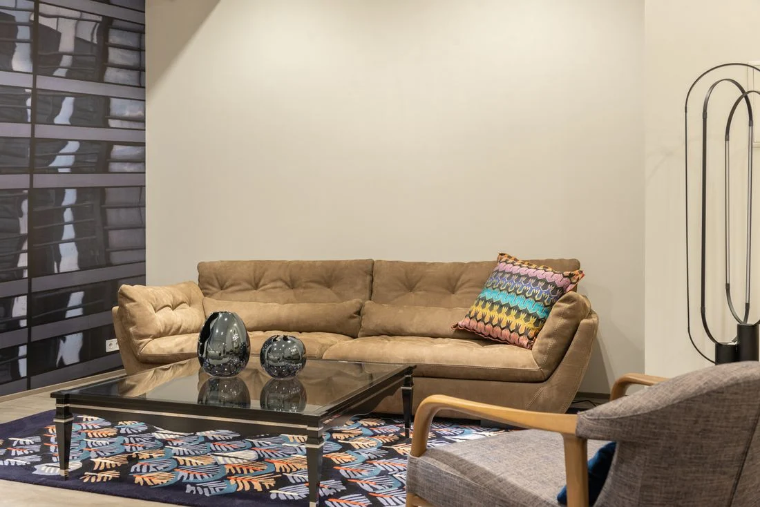 Tan sofa with a wooden armchair and patterned rug