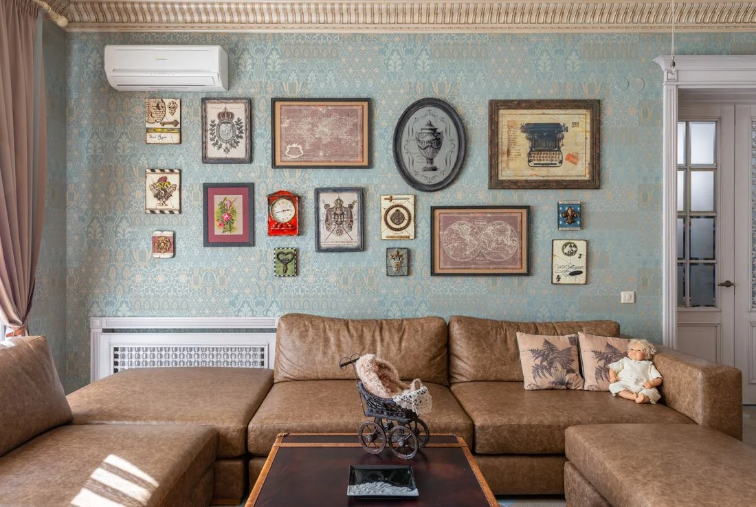 Brown sectional sofa beneath collected artwork near a doorway