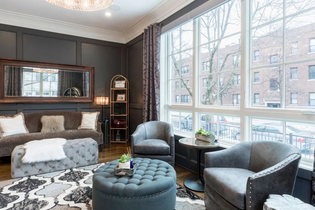 Round tufted ottoman among upholstered living room chairs
