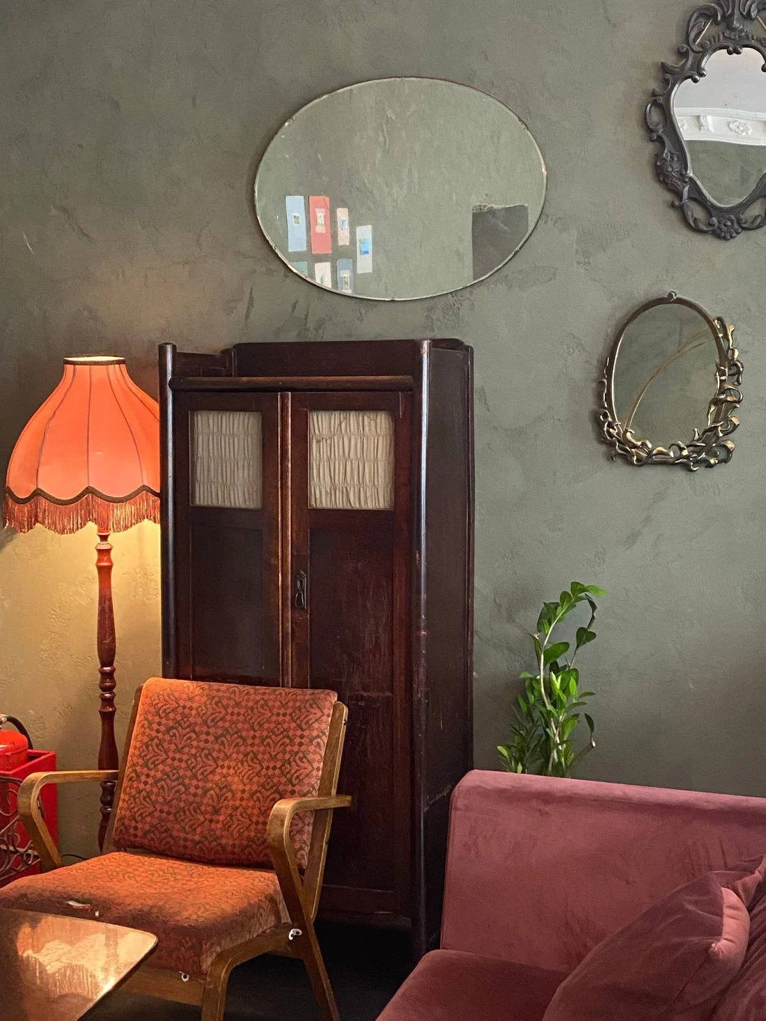 Vintage wooden cabinet, upholstered chair, and decorative mirrors