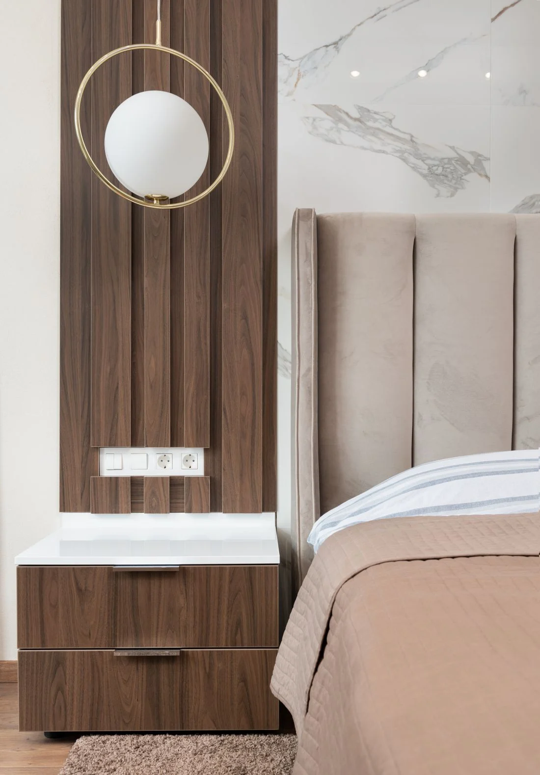 Small bedside drawer unit next to a tall upholstered headboard