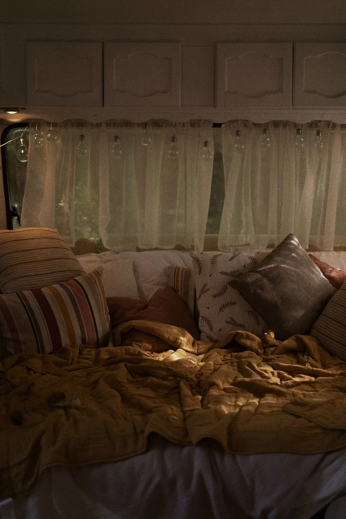 Bed layered with textured pillows and blankets in soft light
