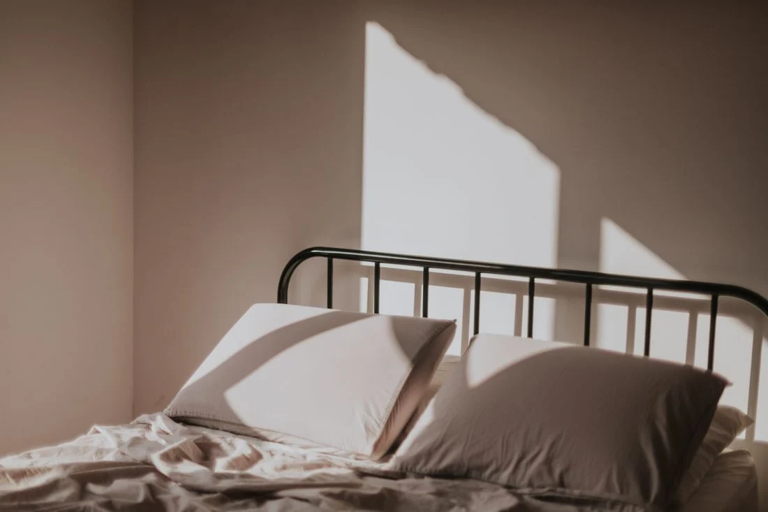 Sunlit bedding on a simple metal bed frame