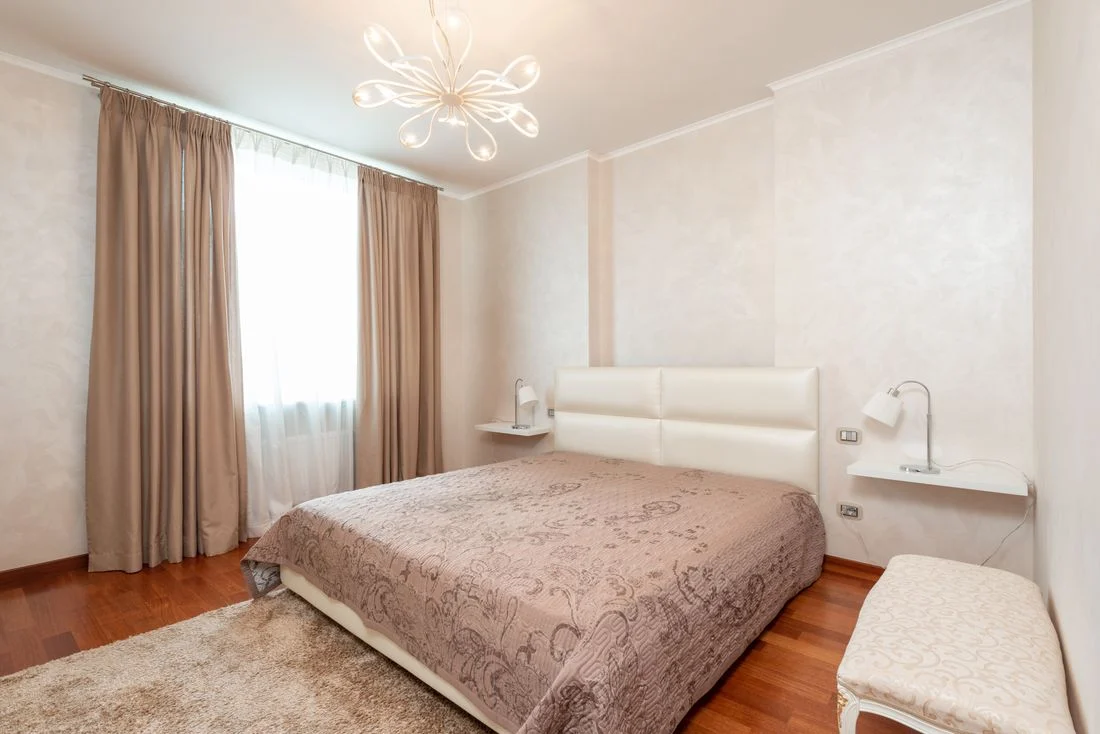 Upholstered bedroom bench at the foot of a made bed