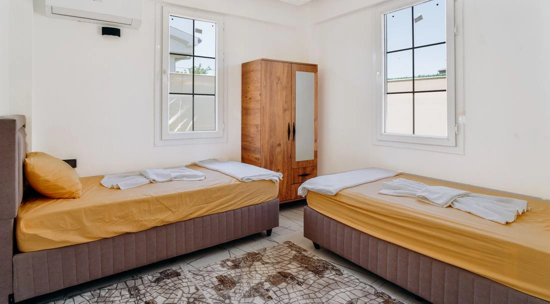 Two separate beds with yellow covers and a shared rug