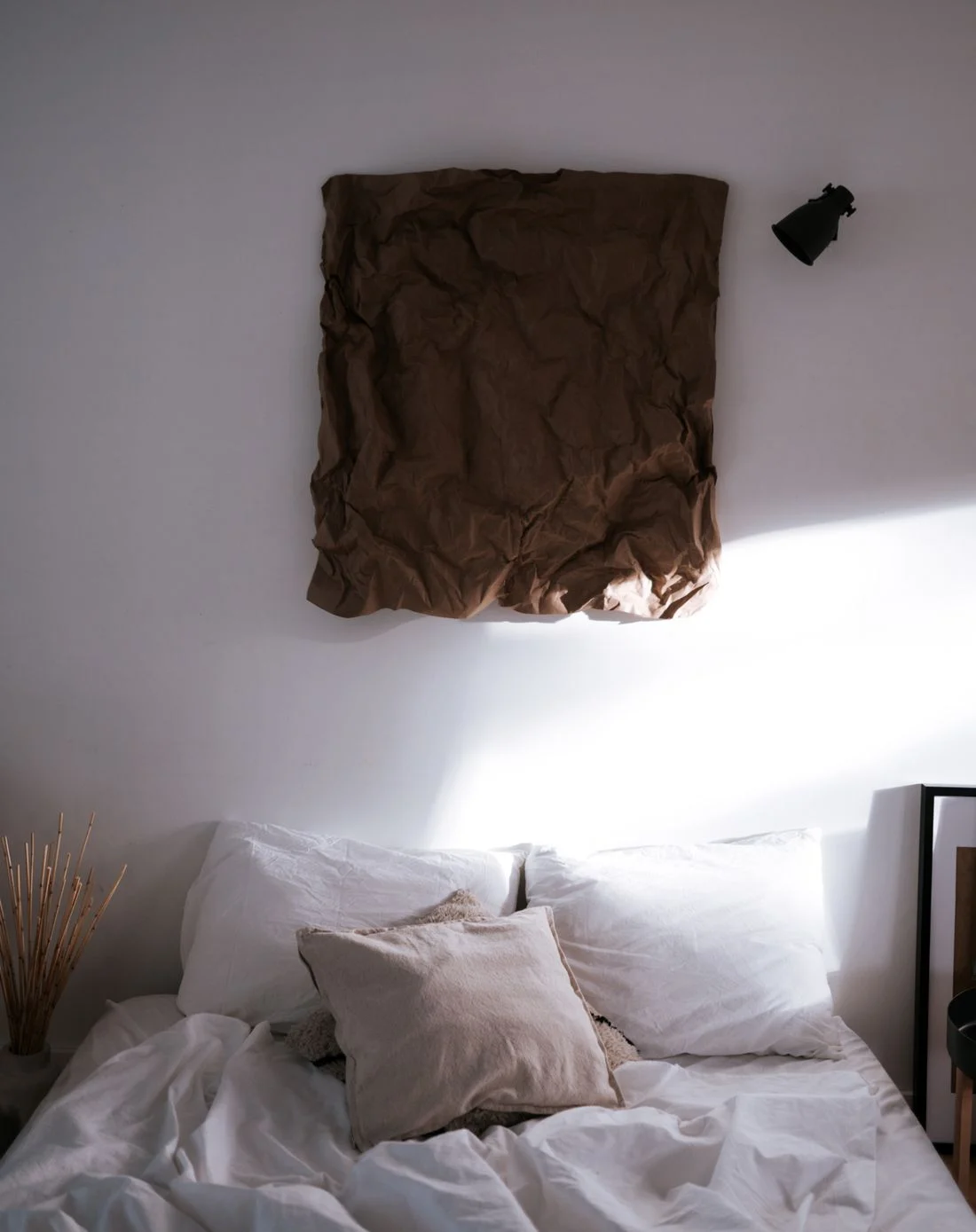 White bedding and cushions in a sunlit bedroom
