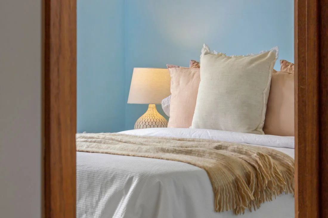 Pale blue bedroom wall with cream bedding and a wooden frame