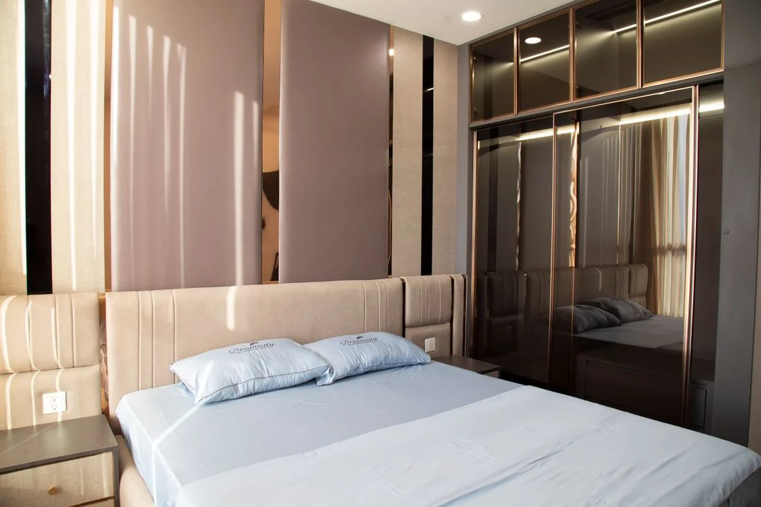 Upholstered bed beside a mirrored wardrobe