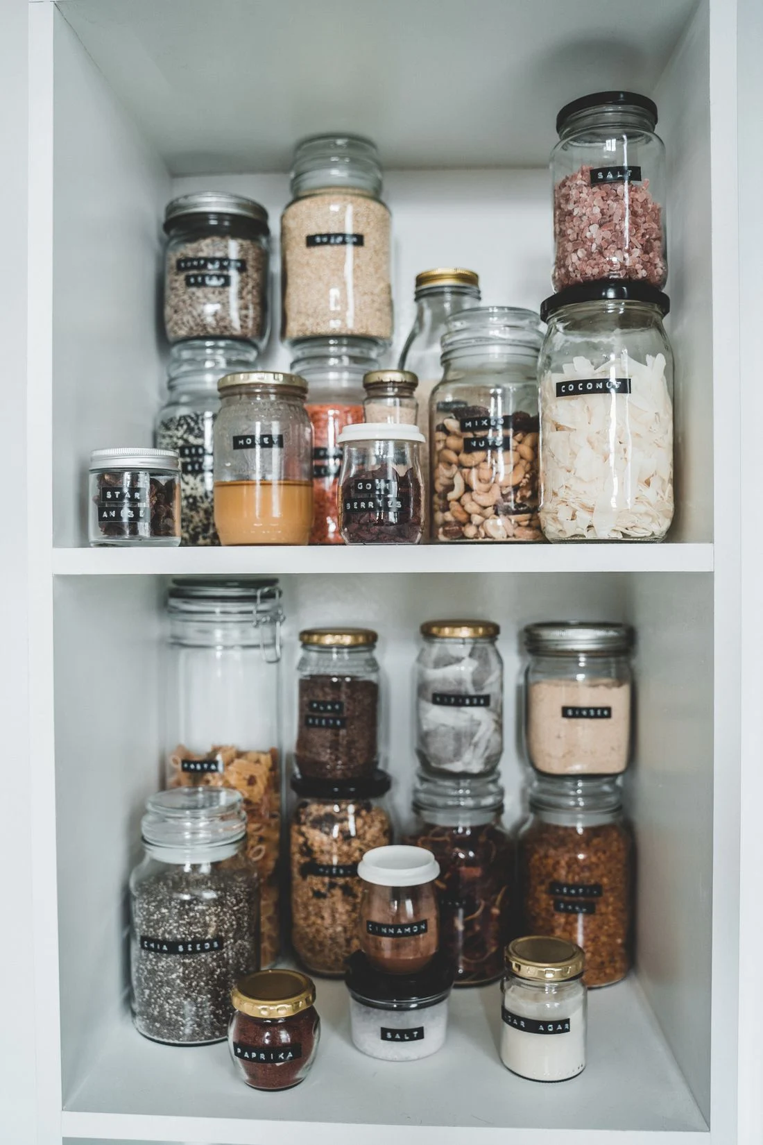Labeled pantry jars on white shelves