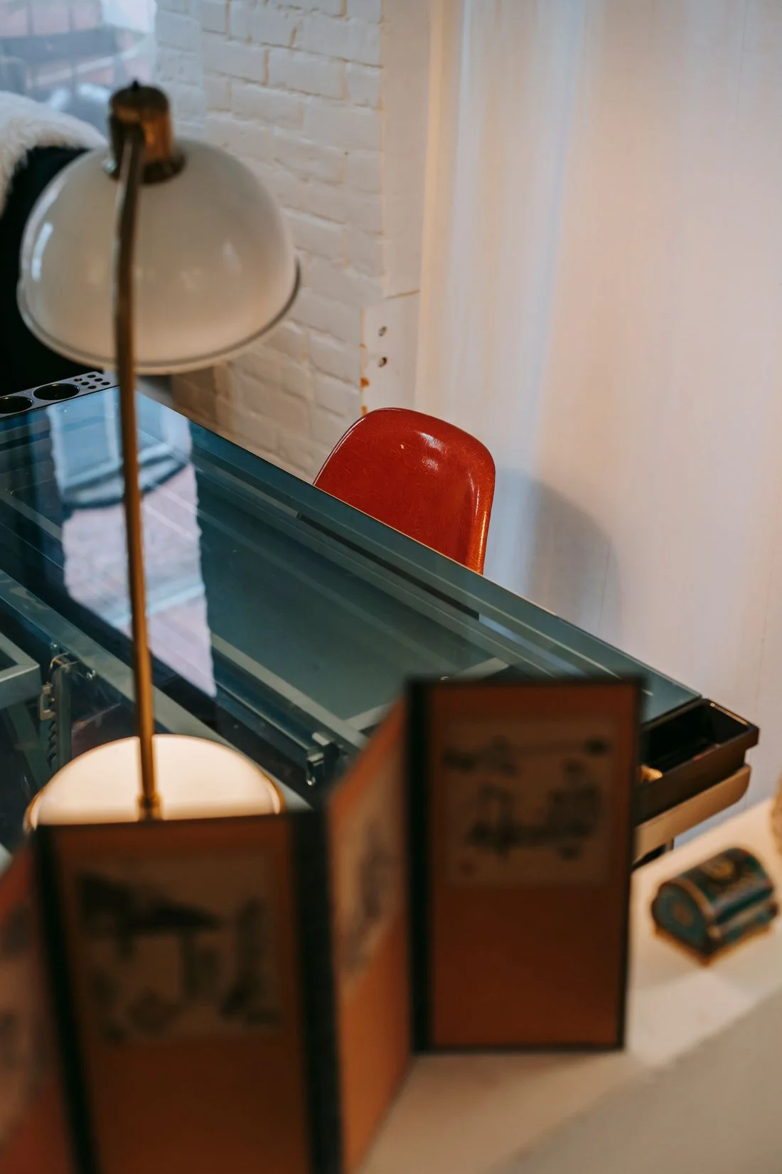 Lamp on a glass desk beside a red chair