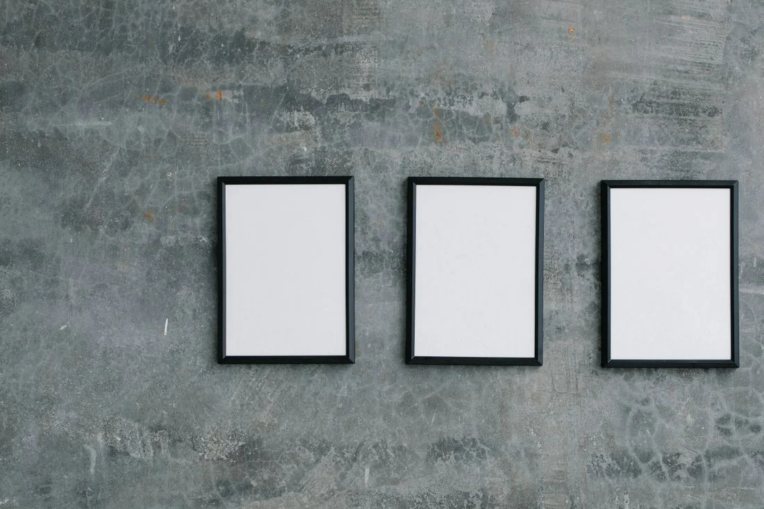 Three empty frames aligned on a textured wall