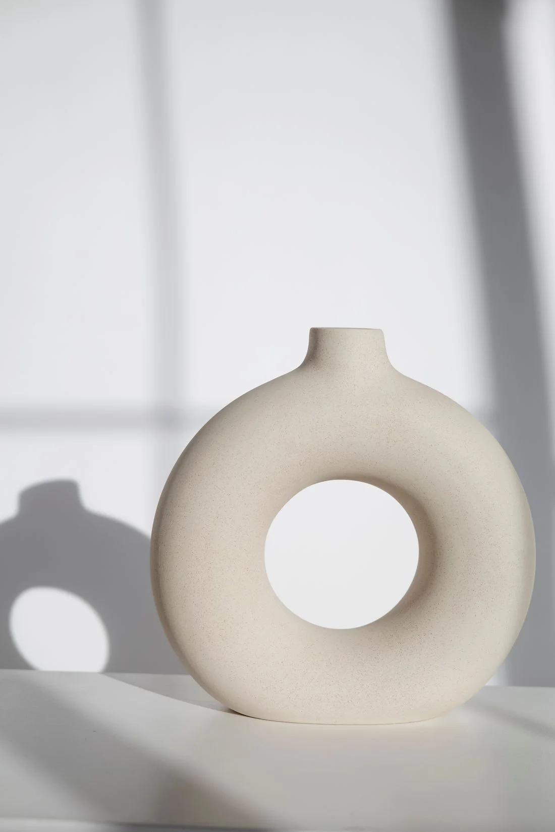 Circular white ceramic vase with soft shadows