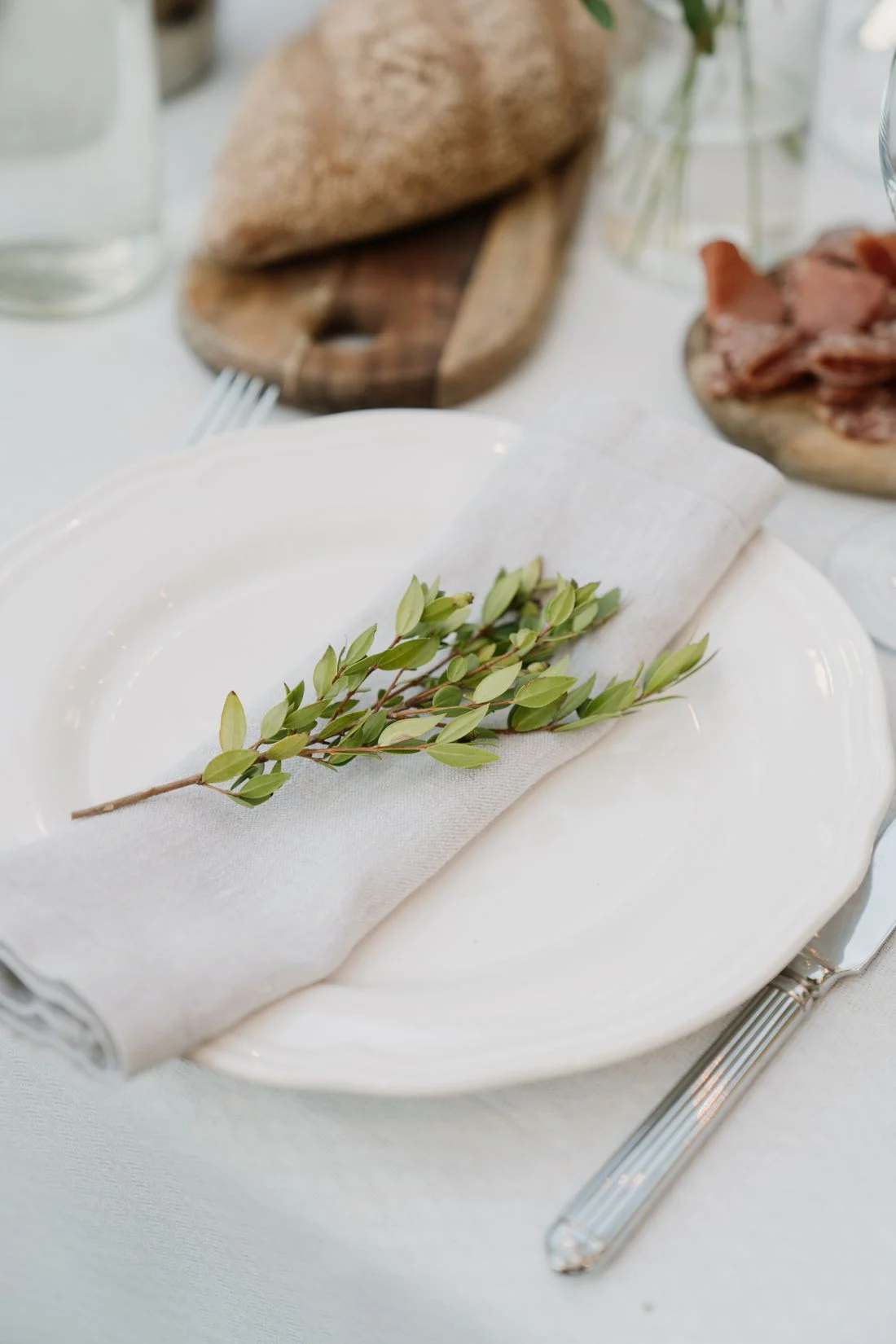 White plate with a linen napkin and greenery