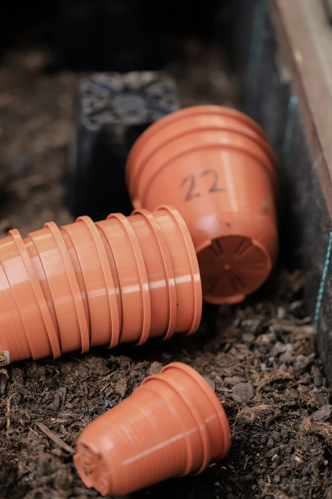 Stacked terracotta-colored plastic nursery pots on soil